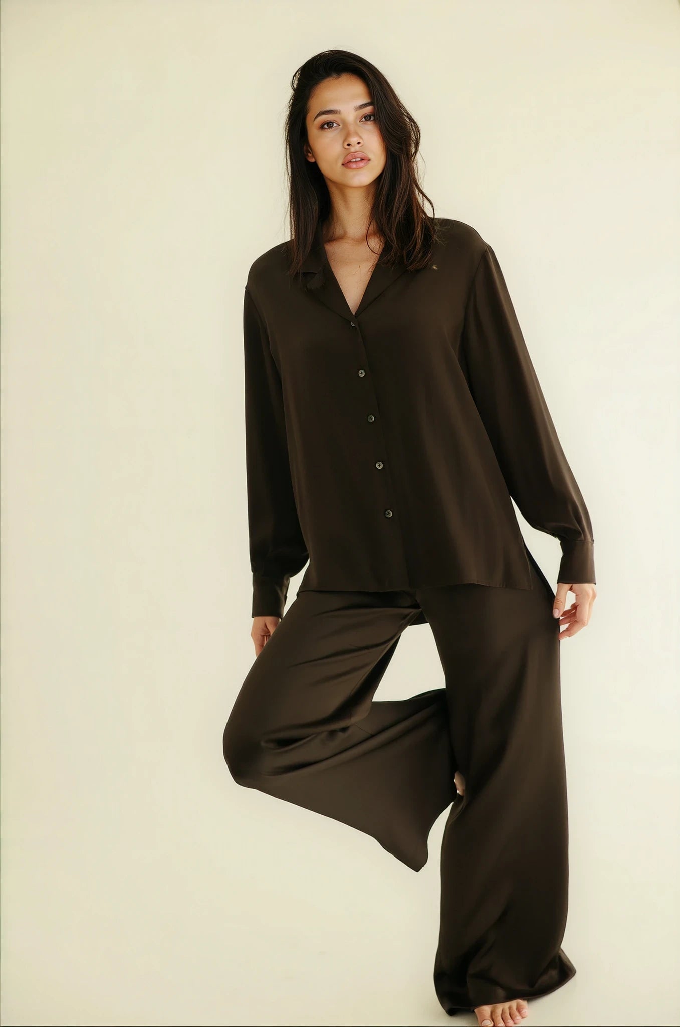 Woman wearing a brown pajama set against a plain background
