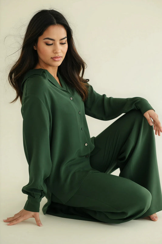 Woman wearing a green NOTTO Silk set outfit sitting on a white floor.