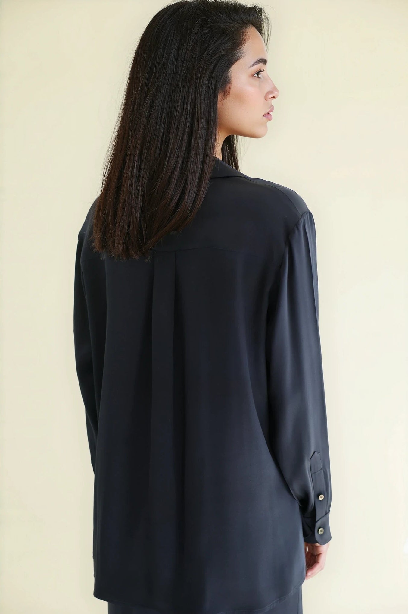 Woman wearing a navy Notto silk shirt against a beige background