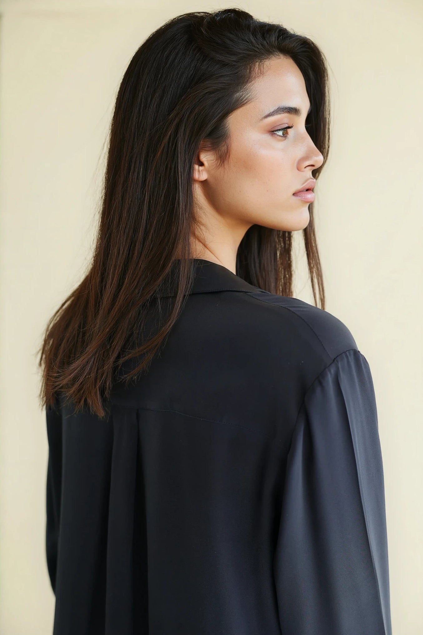 Woman wearing a navy silk Notto shirt against a beige background