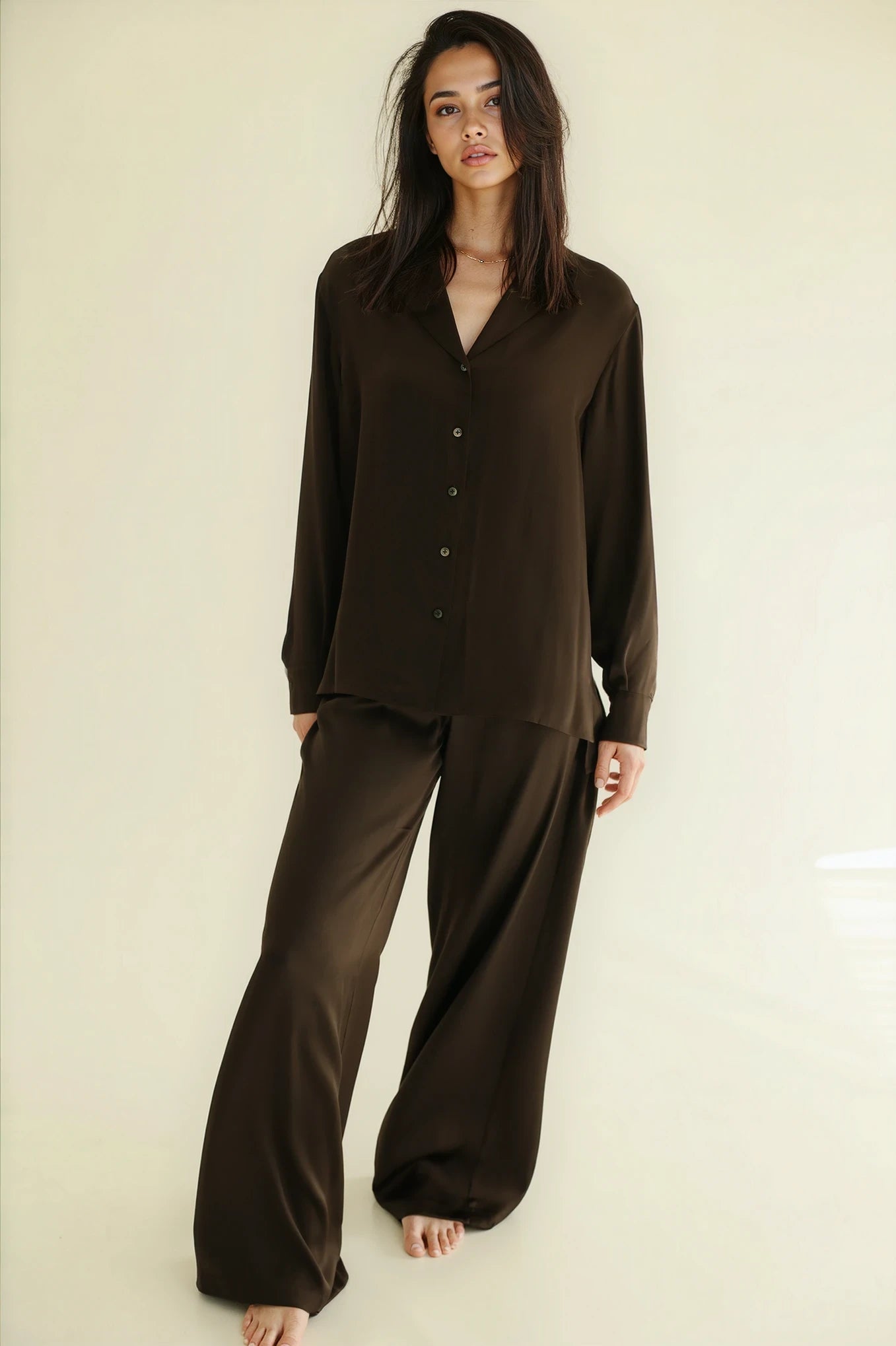 Woman wearing a brown pajama set against a plain background