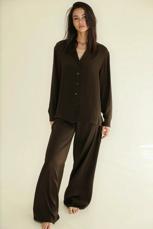 Woman wearing a brown pajama set against a plain background